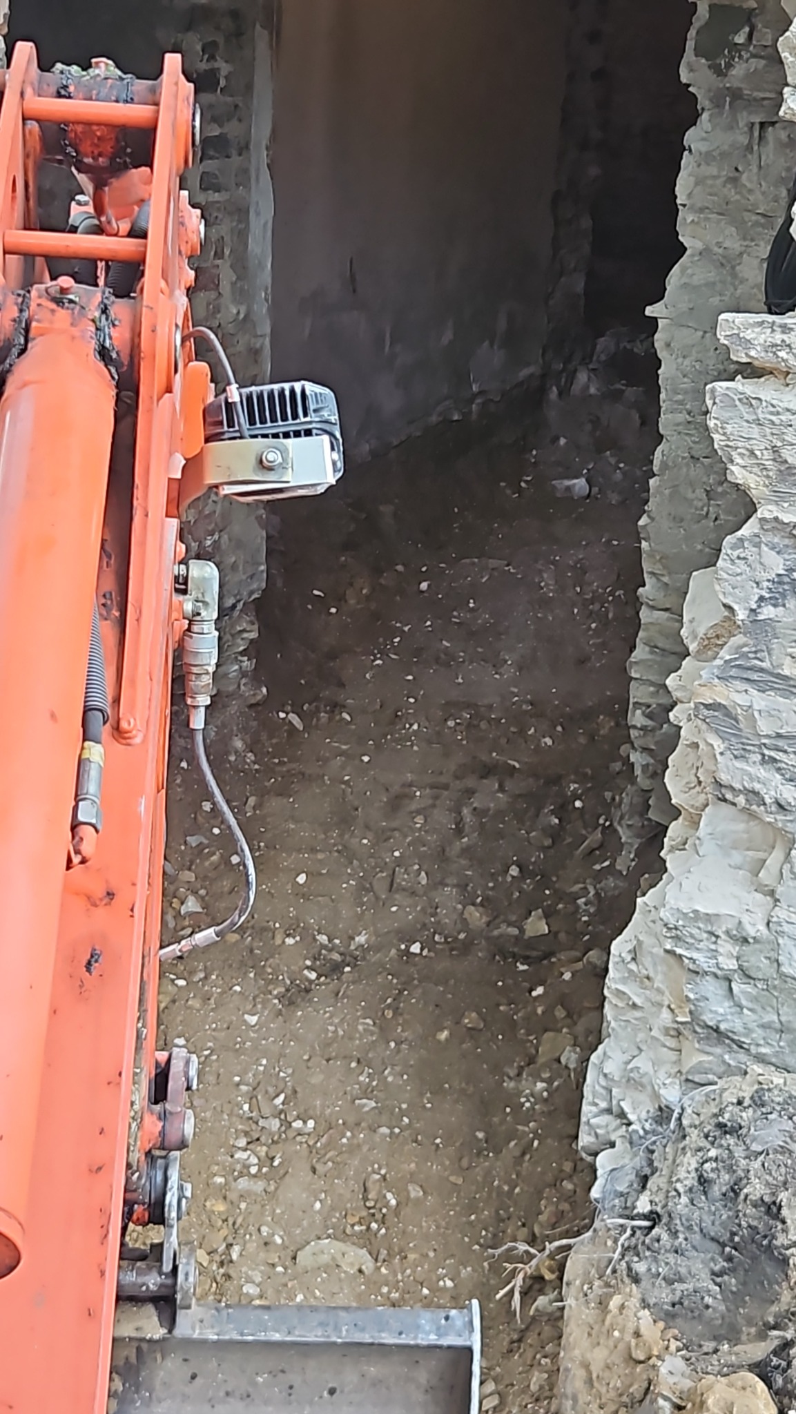 Pomarańczowa koparka w trakcie wykopu pod fundamenty w Jaworznie. Widoczne narzędzia i świeżo naruszona ziemia.