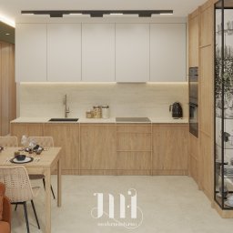 Modernointerno - Jasna kuchnia z drewnianymi szafkami, nakrytym stołem i rośliną w rogu. Nowoczesne oświetlenie i minimalistyczny design. Widok na część jadalną z sofą.