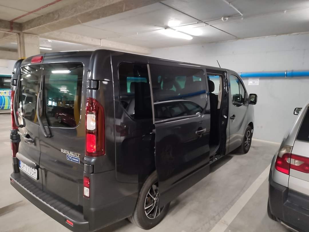 Czarny van Renault Trafic z otwartymi przesuwnymi drzwiami, zaparkowany w garażu podziemnym, widoczny numer rejestracyjny