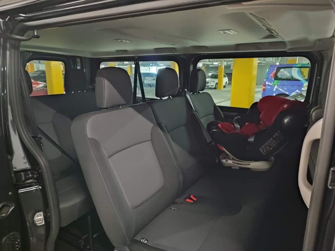 Wnętrze czarnego busa z szarymi siedzeniami i czerwono-czarnym fotelikiem dziecięcym, zaparkowanego w garażu podziemnym w Stronie Śląskie.