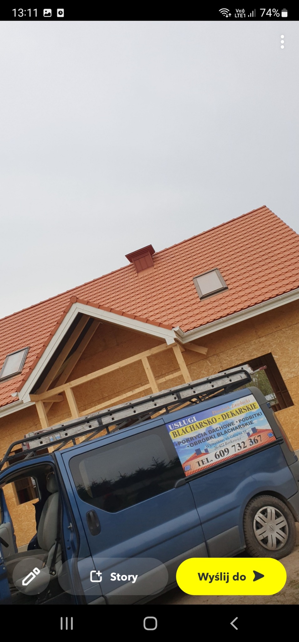 Nowy dach z dachówki ceramicznej na budynku w trakcie budowy, widoczny częściowo samochód firmy dekarskiej z reklamą na boku i drabina na dachu pojazdu.