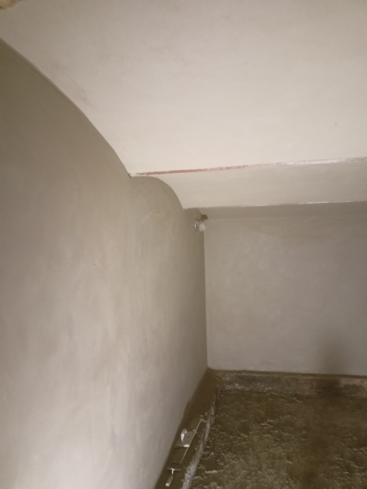 Wnętrze pomieszczenia po nałożeniu gładzi gipsowej na ściany i sufit, widoczny surowy stan podłogi.