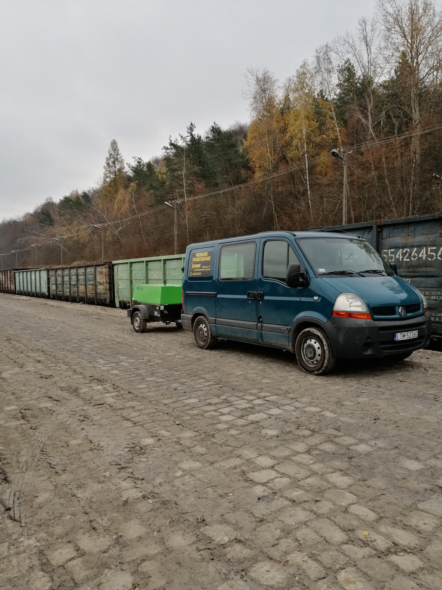 Mobilny zestaw do oczyszczania powierzchni: bus z przyczepą zawierającą urządzenie PDP 35, zaparkowany obok wagonów kolejowych.