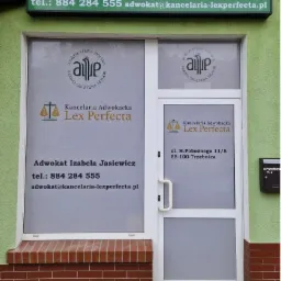Fasada budynku z szyldem i naklejkami na drzwiach wejściowych informującymi o Kancelarii Adwokackiej Izabela Jasiewicz Lex Perfecta, z podanym numerem telefonu i adresem e-mail oraz adresem siedziby.