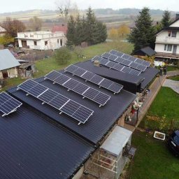 Nortmar Oddział Opole - Instalacja fotowoltaiczna na dachu budynku gospodarczego z blachy trapezowej, widok z góry na wiejski krajobraz i zaparkowany samochód.