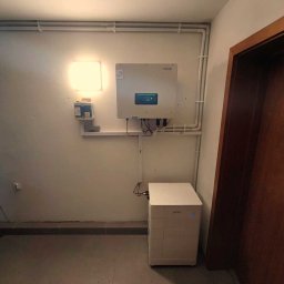 Nortmar Oddział Opole - Biały inwerter fotowoltaiczny marki Sofar oraz moduł magazynu energii w jasnym pomieszczeniu z widoczną instalacją elektryczną.