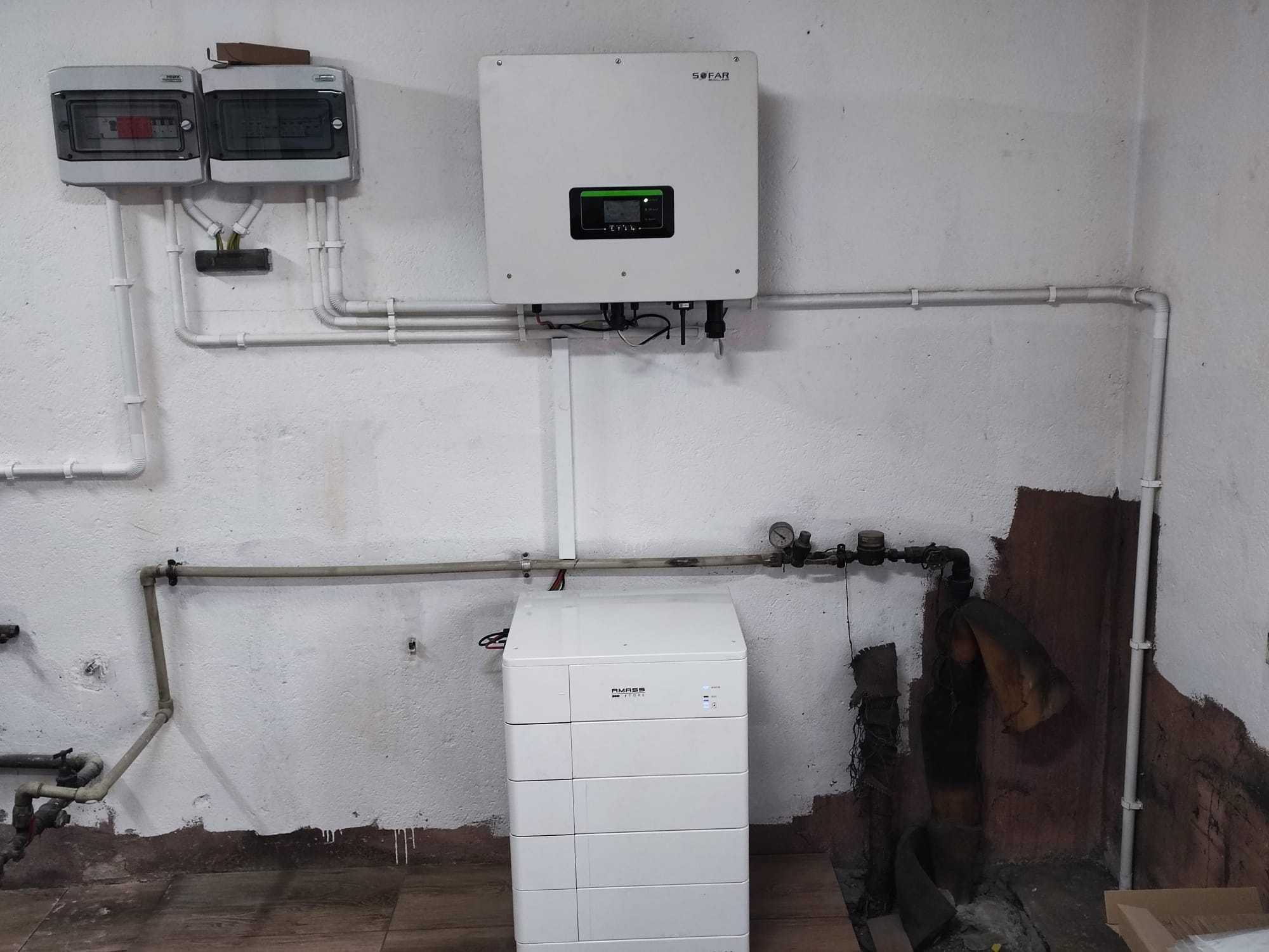 Instalacja magazynu energii Amass w Opolu, widoczny inwerter Sofar Solar, białe rury instalacyjne i skrzynki elektryczne na tle surowej ściany.