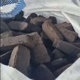 Brykiety opałowe w worku jutowym z niebieskim sznurkiem, widoczne nieregularne kształty i struktura materiału.