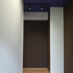 Ekipa Malarska - Pomieszczenie po malowaniu: białe i brązowe ściany, ciemnoniebieski sufit z oświetleniem punktowym. Podłoga wyłożona panelami w odcieniach drewna.