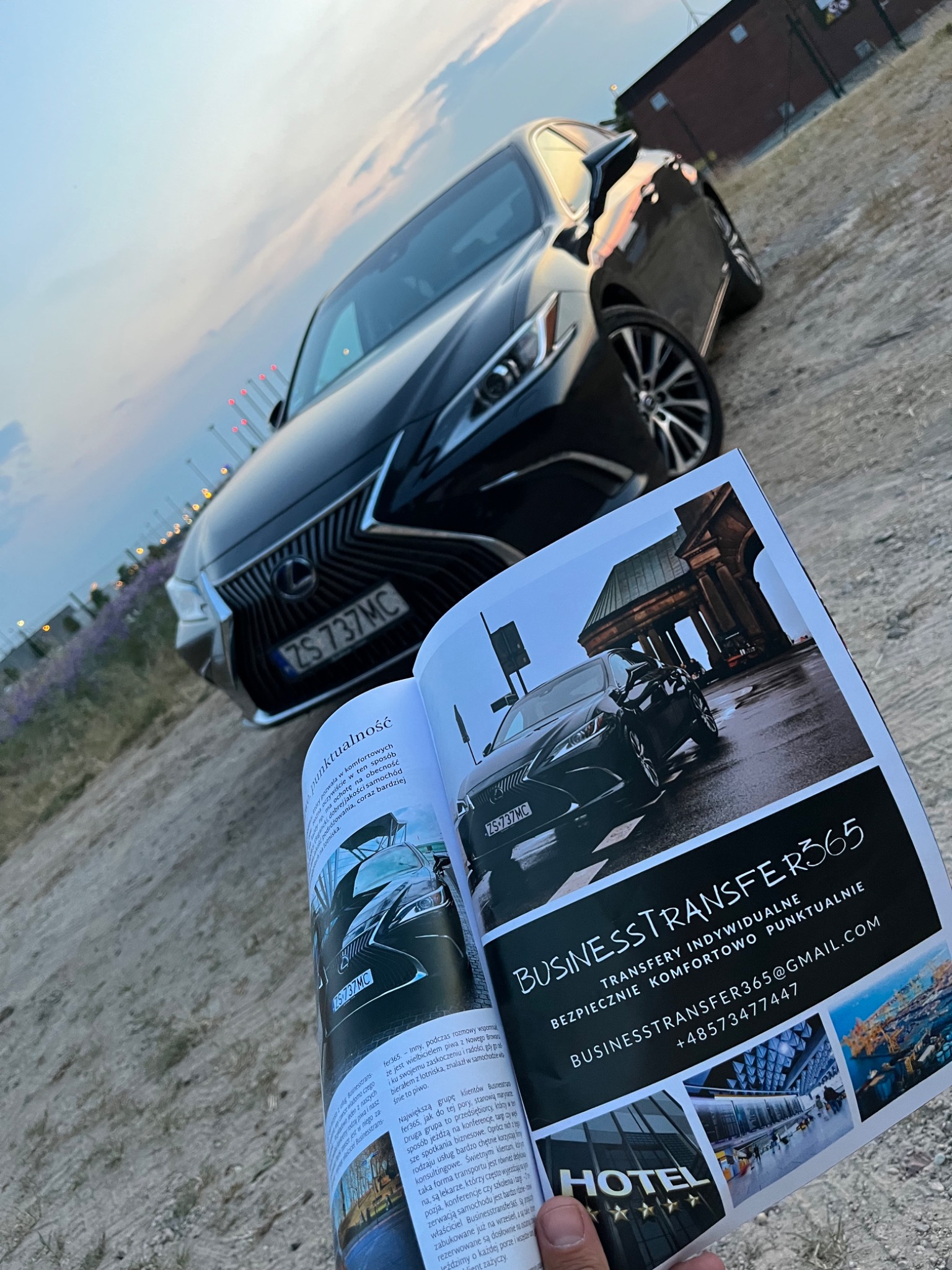 Czarny Lexus z numerem rejestracyjnym ZS 737MC w tle, a na pierwszym planie otwarta strona magazynu reklamującego firmę Business Transfer 365 z ofertą transferów indywidualnych.