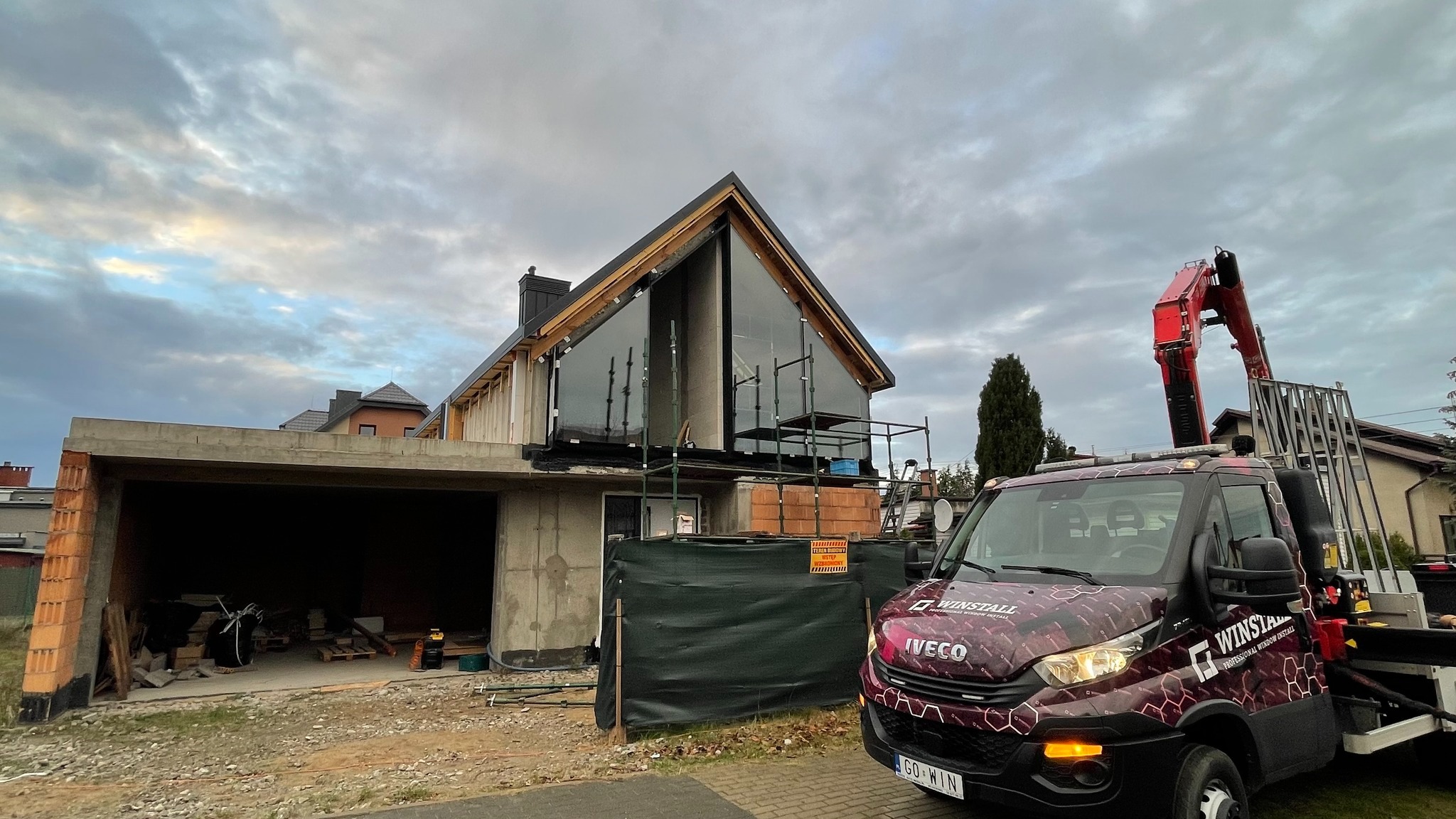 Montaż dużych okien fasadowych w domu jednorodzinnym w Übach-Palenberg, widoczny samochód dostawczy z dźwigiem i logo firmy WINSTALL.