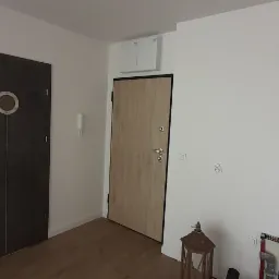 Wnętrze mieszkania po remoncie: dwie r&oacute;żne drzwi wewnętrzne, świeżo pomalowane ściany na biało, widoczne elementy instalacji.