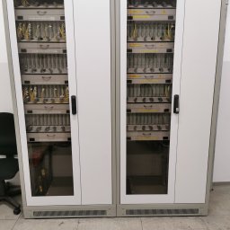 FiberOptic - Dwie szafy rackowe z panelami krosowniczymi światłowodowymi marki R&M, widoczne kable światłowodowe i oznaczenia modułów.