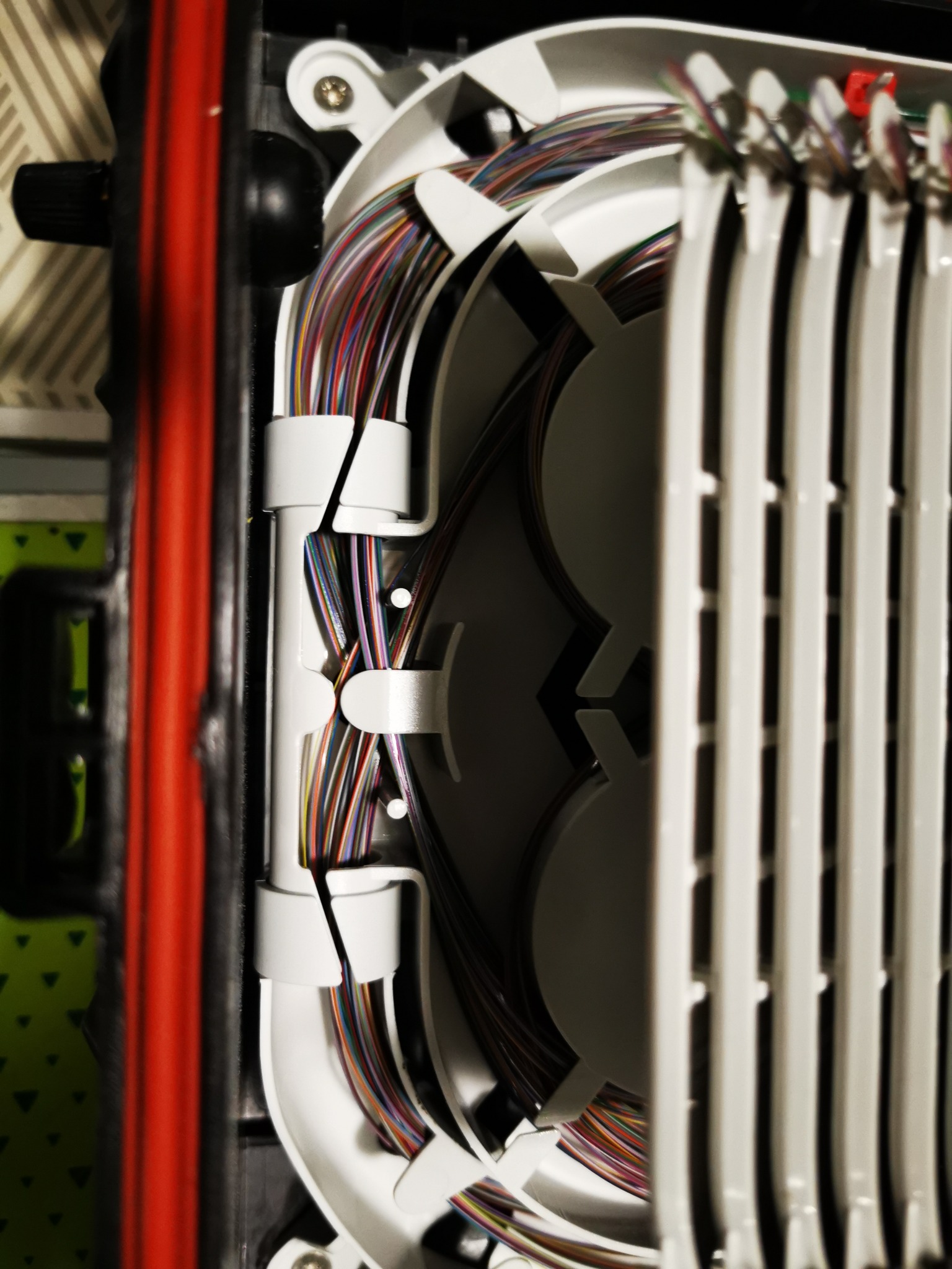 Szczegółowe ujęcie rozdzielnicy światłowodowej z uporządkowanymi kablami w różnych kolorach, zainstalowanej przez firmę z Warszawy. Widoczne precyzyjne ułożenie przewodów wewnątrz obudowy.