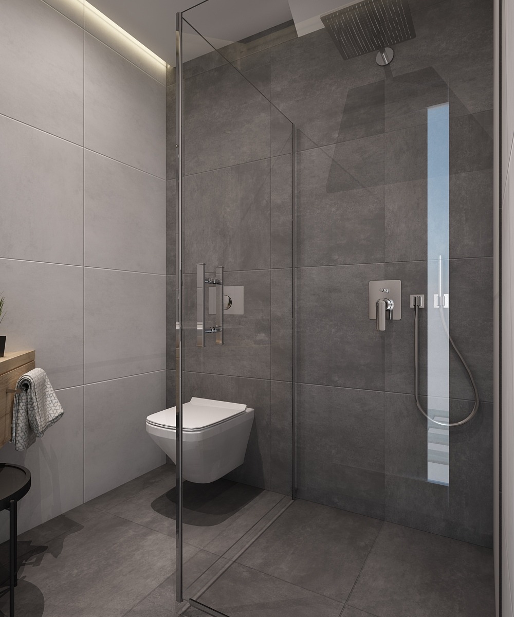 Nowoczesna łazienka z szarymi płytkami, kabiną prysznicową typu walk-in ze szklaną ścianą, podwieszaną toaletą i deszczownicą.