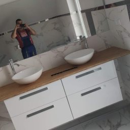 Tob-Rem Tobiasz Żmud - Nowoczesna łazienka we Wrocławiu z umywalkami nablatowymi, drewnianym blatem i białymi szafkami z szufladami, wykończona marmurowymi płytkami i dekoracyjnym pasem płytek strukturalnych.