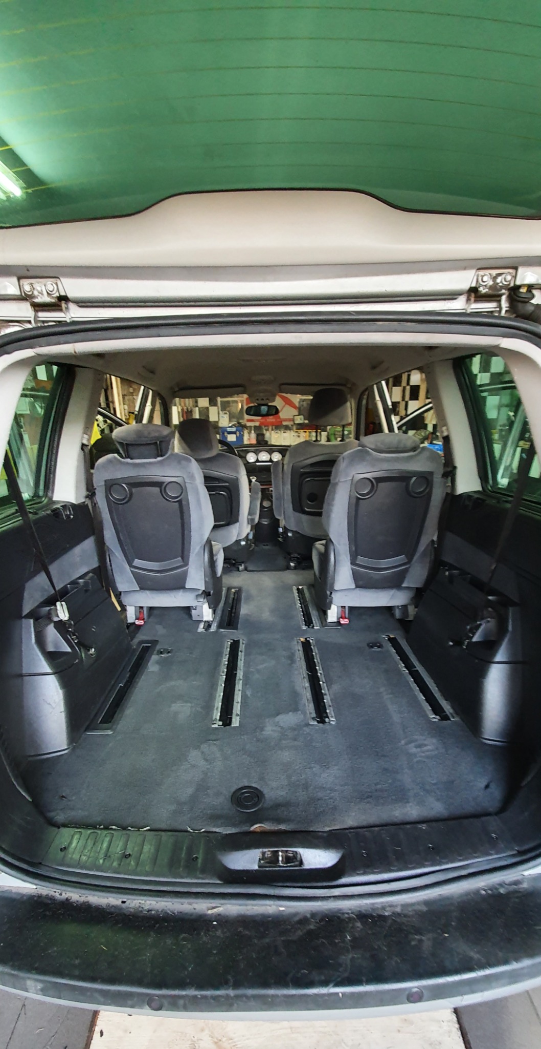 Wnętrze samochodu typu van z wyjętymi siedzeniami, widoczne szyny montażowe na podłodze, przygotowane do czyszczenia tapicerki.