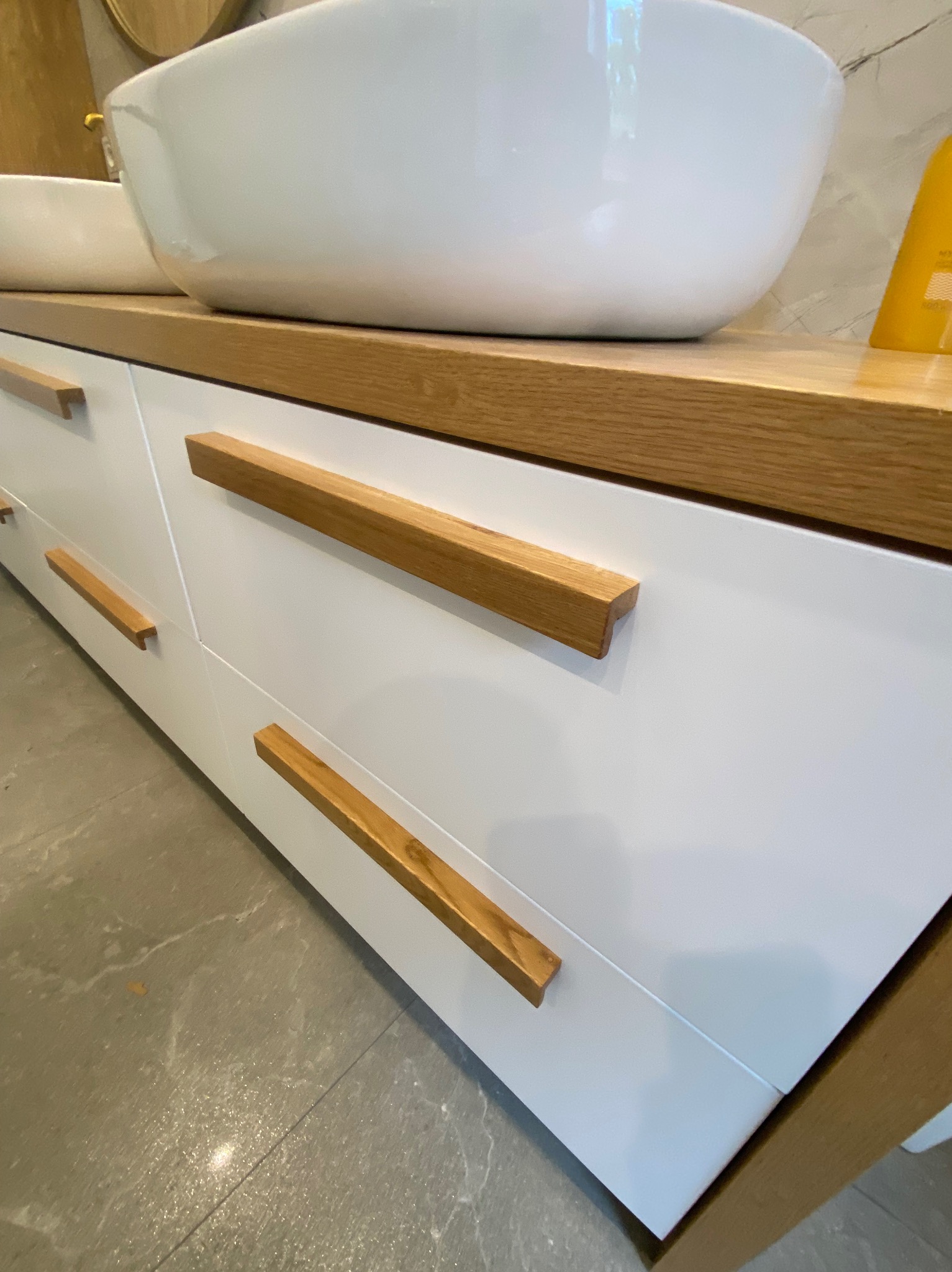 Nowoczesna łazienka: Biała szafka pod umywalkę z drewnianym blatem i uchwytami, owalna umywalka nablatowa.