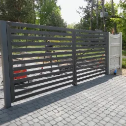 Nowoczesna, pozioma brama wjazdowa z metalowymi poprzeczkami, widoczny sprzęt spawalniczy w tle, ułożona kostka brukowa.