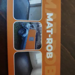 Ujęcie z góry na pomarańczową kartę reklamową firmy MAT-ROB z trzema zaokrąglonymi zdjęciami: wnętrze z szarą posadzką, maszyna do wylewki oraz kolejne wnętrze z szarą posadzką.