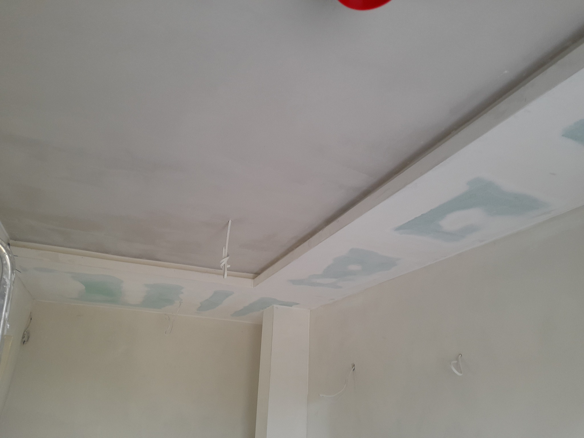 Wnętrze w trakcie prac wykończeniowych: sufit z elementami płyty gipsowej, widoczne łączenia i szpachlowanie. Ściany w jasnym odcieniu, przygotowane do malowania.