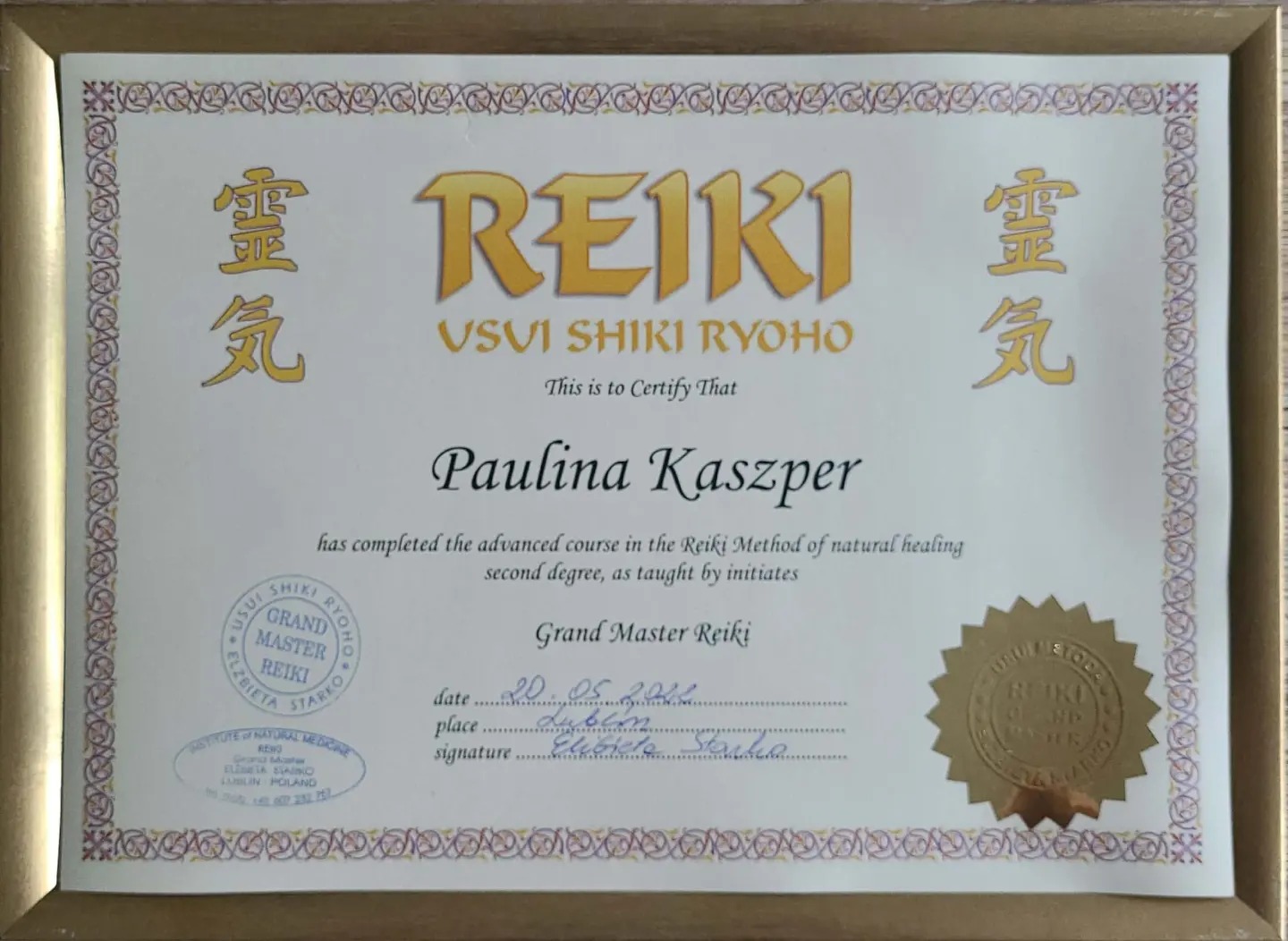 Certyfikat ukończenia kursu Reiki dla Pauliny Kaszper, wydany przez Instytut Medycyny Naturalnej, oprawiony w złotą ramkę.