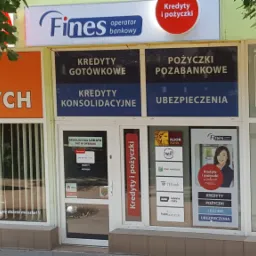 Fasada budynku z szyldem 'Fines operator bankowy' oferującego kredyty i pożyczki, widoczne reklamy różnych banków i firm pożyczkowych, obok salon kosmetyczny.