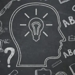Tablica kredowa z rysunkiem głowy z żarówką w środku, otoczona symbolami edukacyjnymi, takimi jak książki, laptop, słuchawki, litery ABC i lupa.