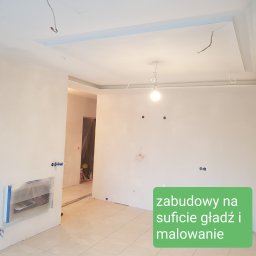 Wykończenia wnętrz -Jacek Stefański - Wnętrze w trakcie remontu: białe ściany po szpachlowaniu i gładzi, przygotowane pod malowanie, z widoczną zabudową sufitu podwieszanego i wystającymi przewodami elektrycznymi, zabezpieczone...
