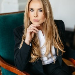 Adwokat Lublin Rozwód Podział Majątku Sprawy Karne Sprawy Cywilne - Portret kobiety w czarnym garniturze, siedzącej w zielonym fotelu. Dłoń podparta pod brodą, spojrzenie skierowane w lewo. Jasne włosy opadają na ramiona.