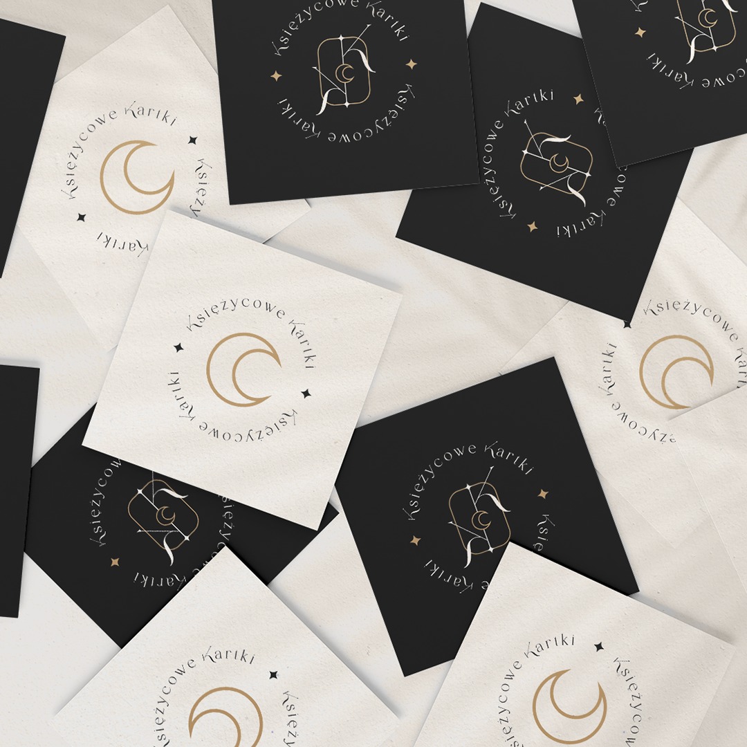 Stos wizytówek w kolorach czerni i beżu z logo 'Księżycowe Kartki', prezentacja identyfikacji wizualnej firmy z Pustkowa.