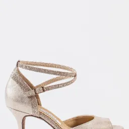 Elegancki, złoty but do tańca z otwartymi palcami i brokatowym paskiem wokół kostki, ustawiony na białym tle.