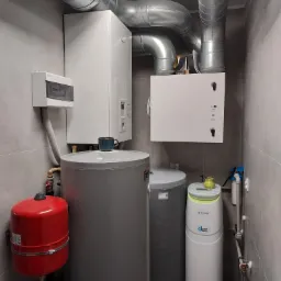 Kotłownia z rekuperatorem Komfovent, zasobnikiem ciepłej wody, naczyniem przeponowym i filtrem wody Klarwod, całość w pomieszczeniu z szarymi płytkami.