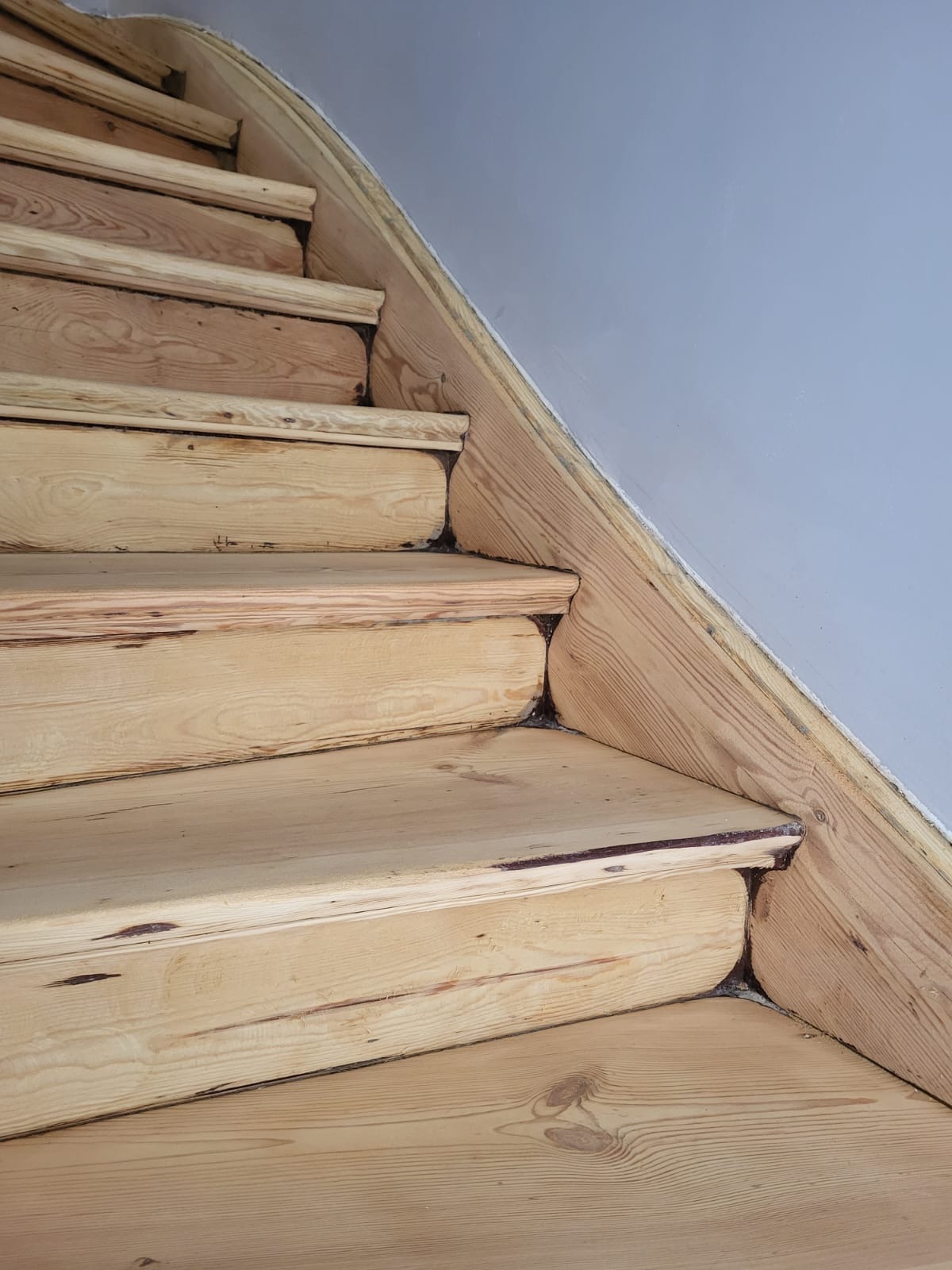 Drewniane schody z widocznymi śladami użytkowania i niedoskonałościami wykończenia, ukazujące naturalną strukturę drewna i połączenia stopni.