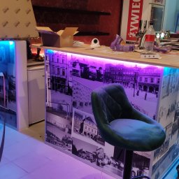 BPZ - Bar z podświetleniem LED, oklejony fototapetą z motywem starego miasta, krzesło barowe, narzędzia i materiały budowlane w trakcie prac wykończeniowych.