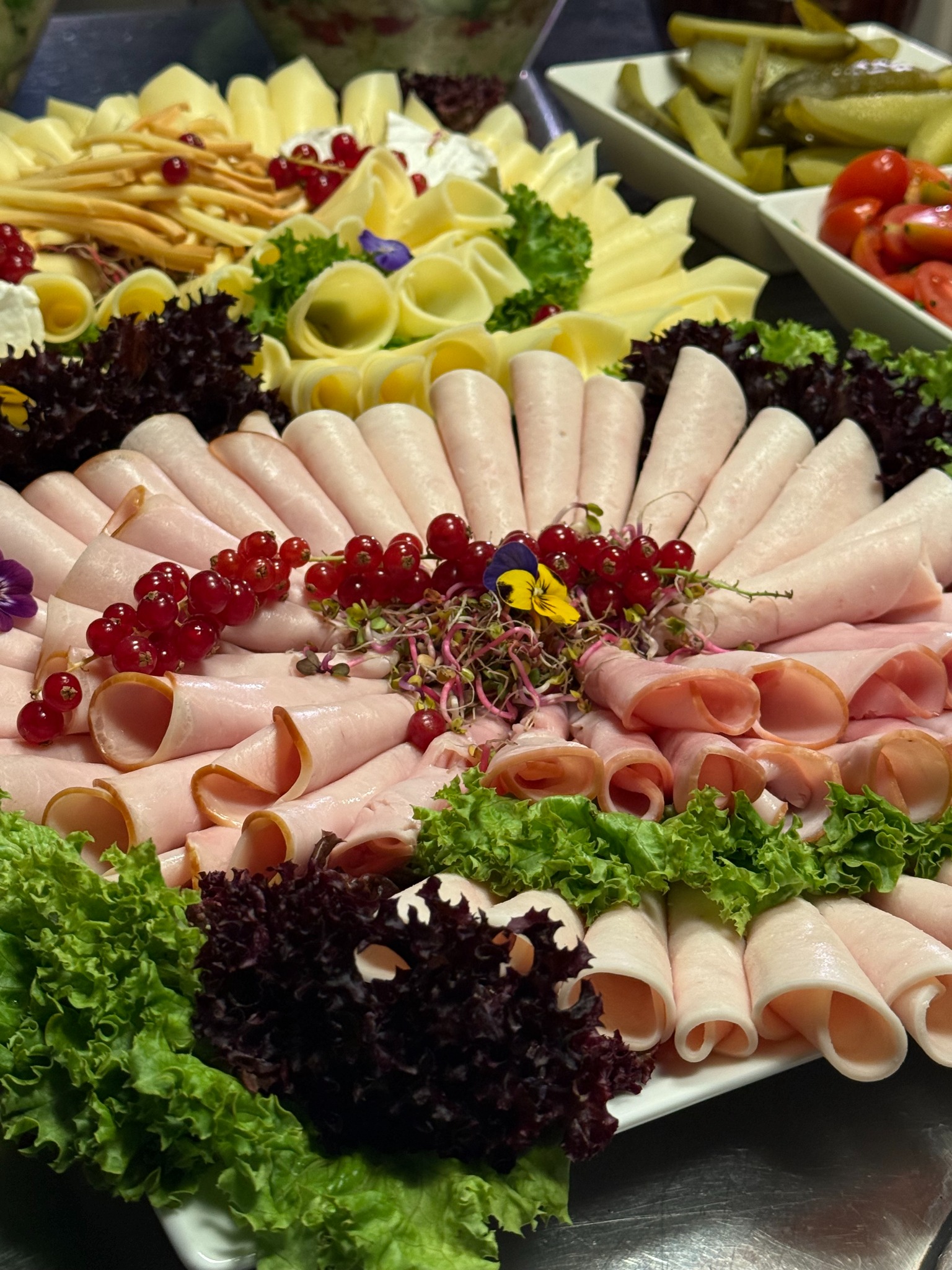 Dekoracyjna taca z wędlinami, serami, sałatą i owocami, idealna na catering świąteczny lub firmowy. Centralny punkt stołu, bogata kompozycja.