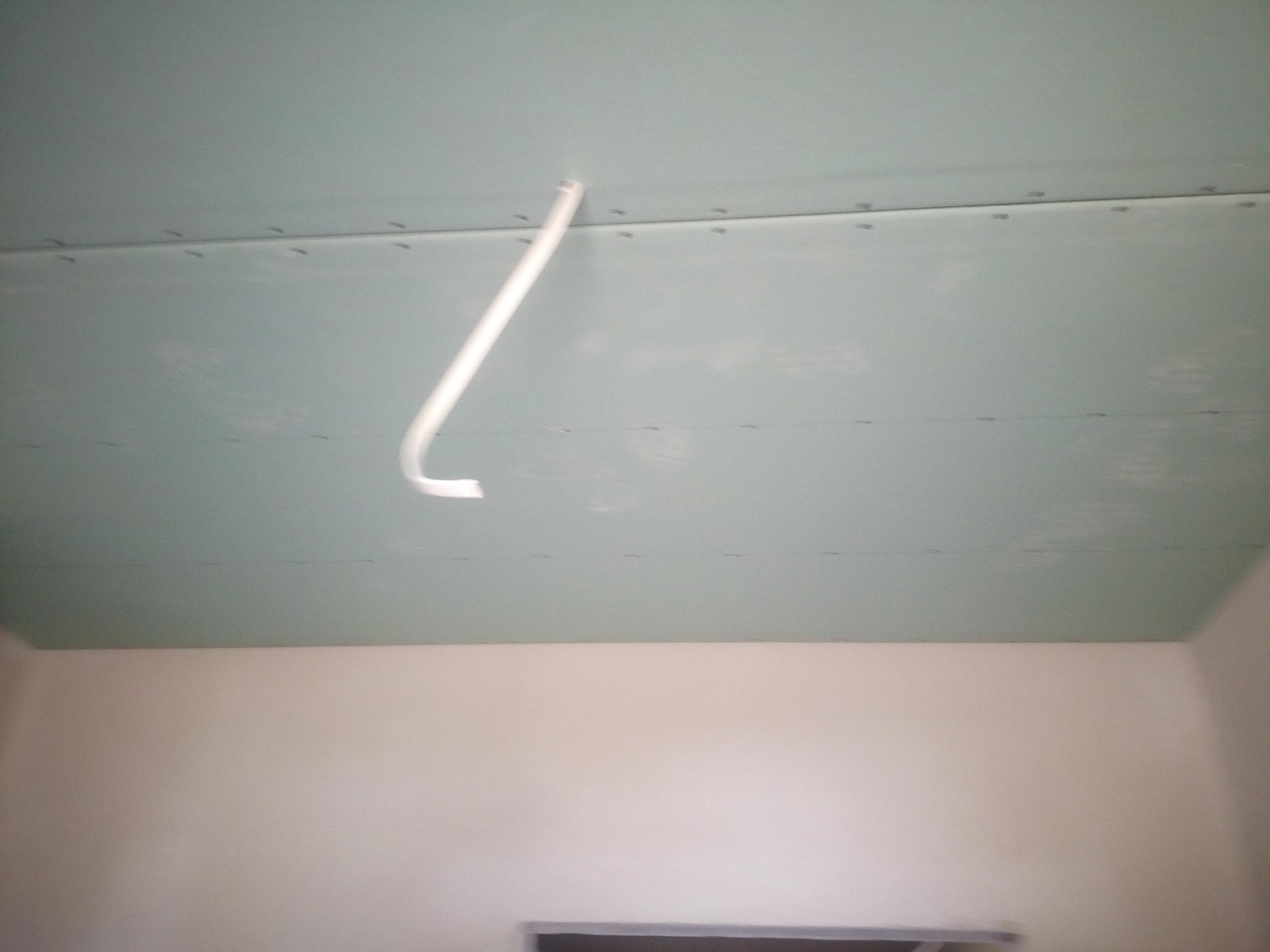 Zamontowany sufit podwieszany z płyt gipsowo-kartonowych, widoczne łączenia płyt i wystający przewód elektryczny.