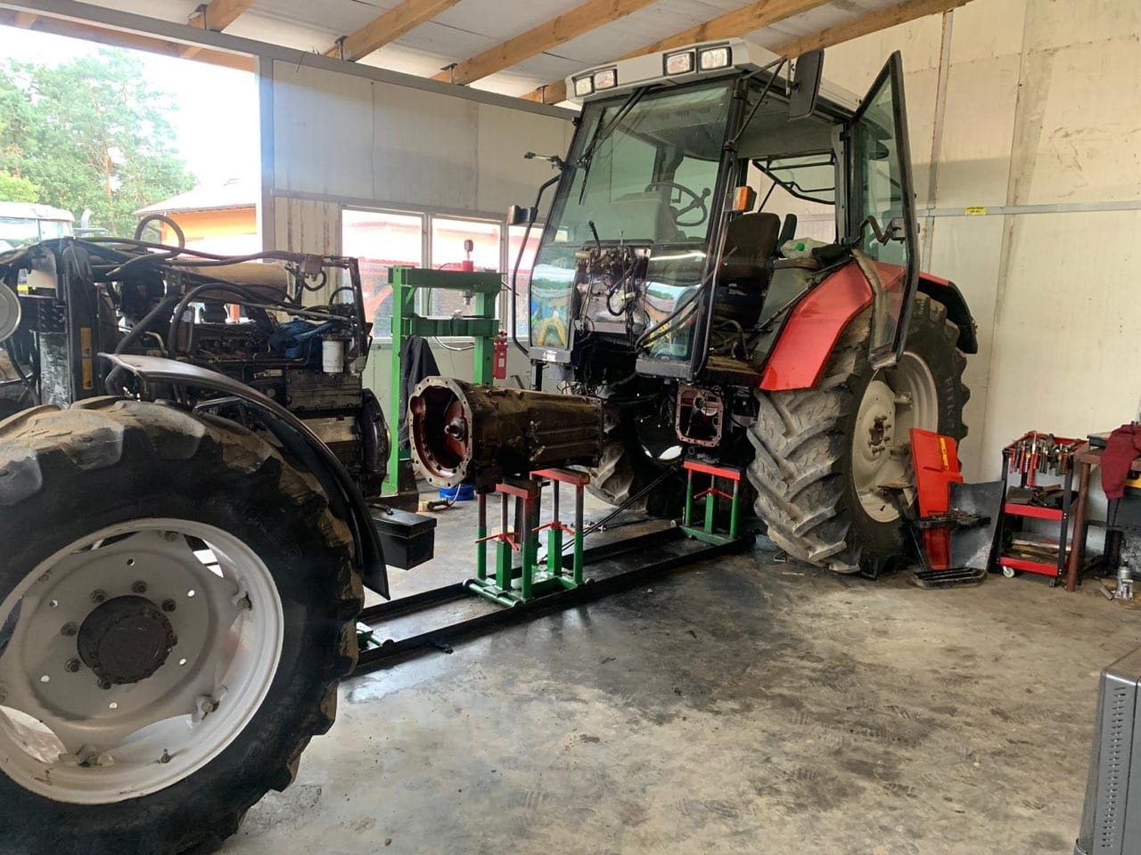 Częściowo rozebrany traktor w warsztacie w Modliborzycach, skrzynia biegów na stojaku, widoczny wózek z narzędziami.