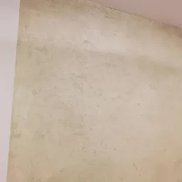 Ściana z efektem betonu architektonicznego w odcieniach beżu i szarości, widoczne nieregularne wzory i faktura, narożnik ściany pomalowany na biało.