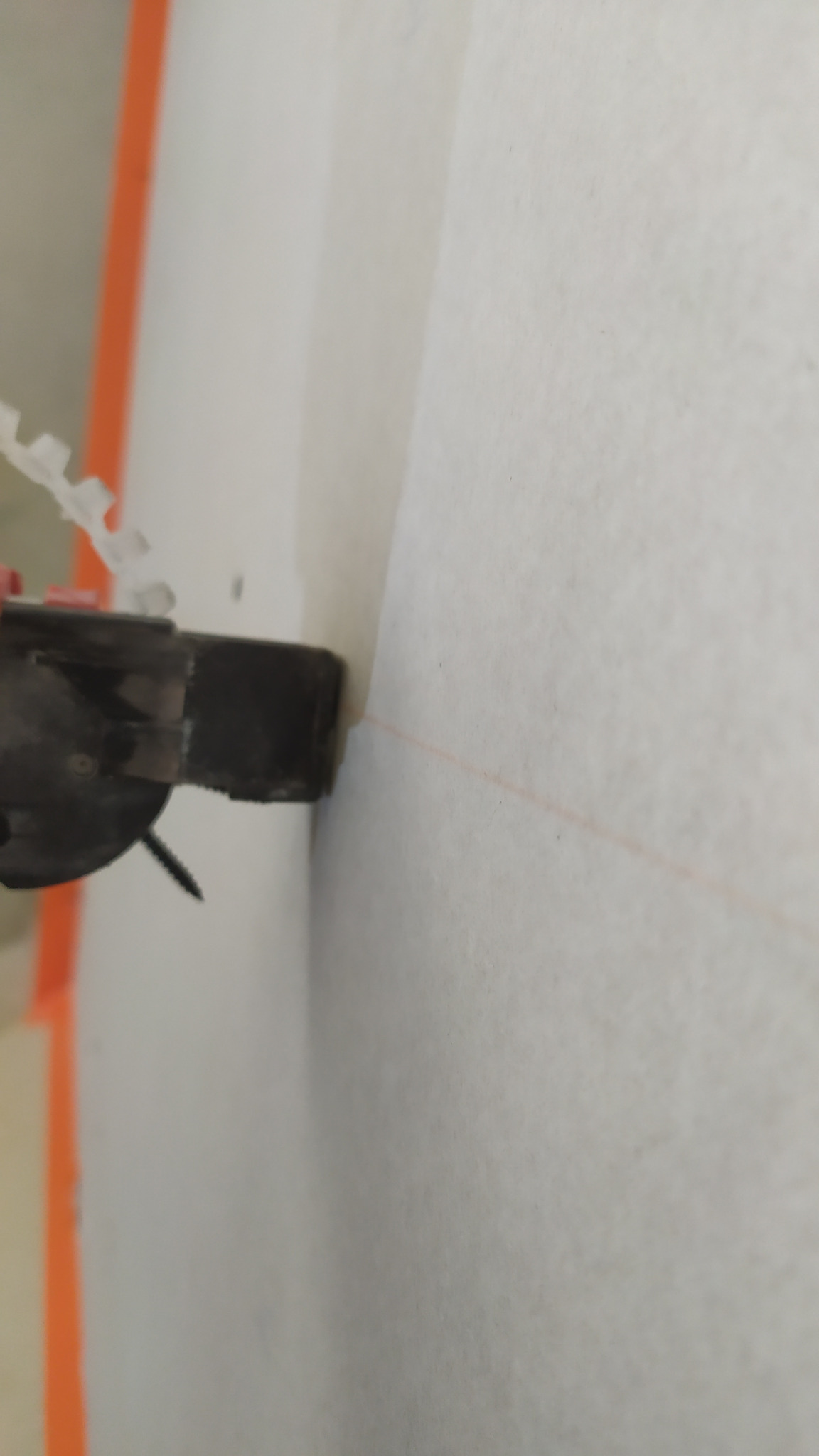 Przybliżenie narzędzia do montażu płyt gipsowo-kartonowych, widoczna linia wyznaczająca poziom na ścianie.