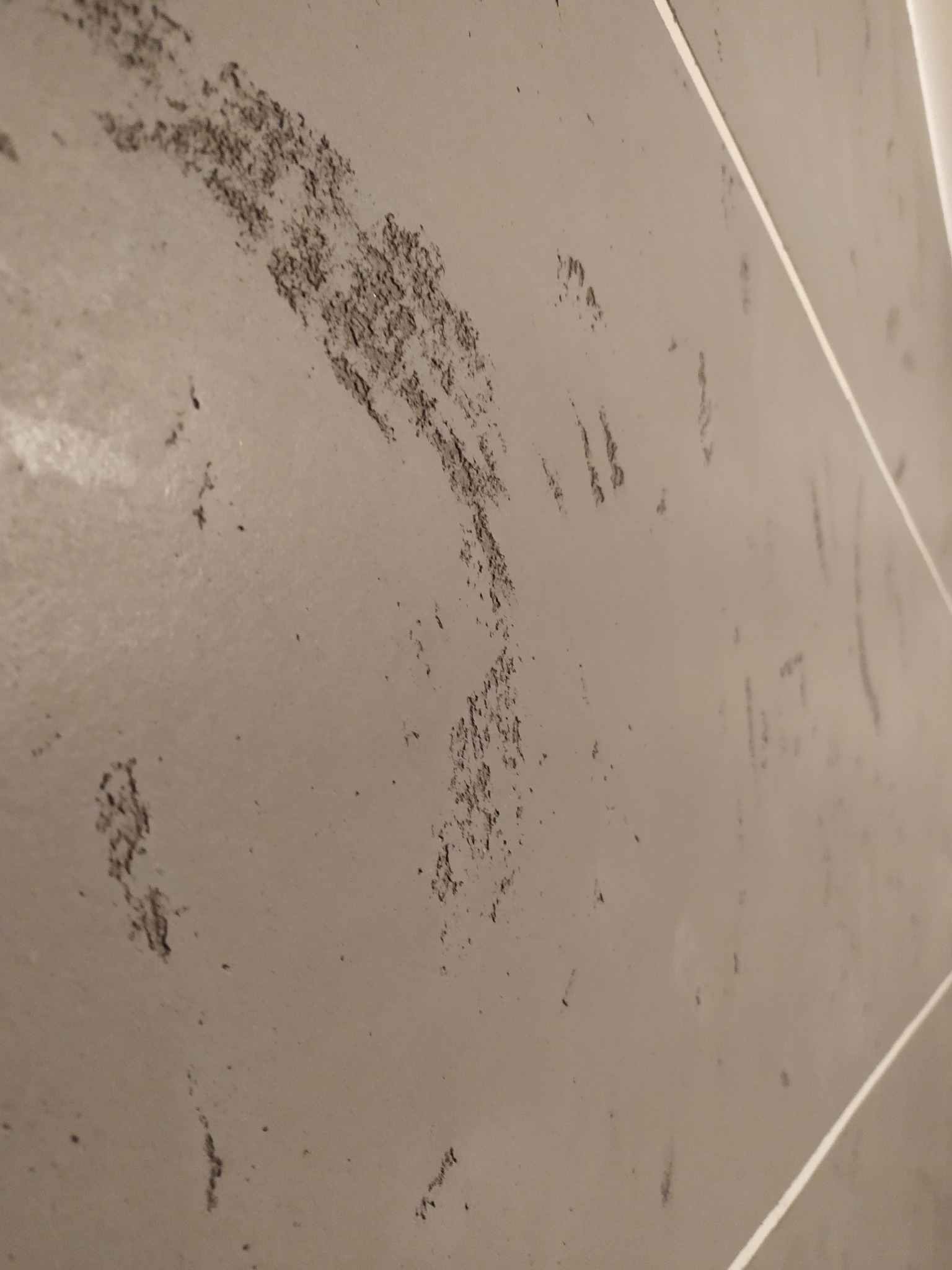 Szara ściana z efektem dekoracyjnym imitującym ślady pędzla lub przetarcia, widoczne fugi między płytami.