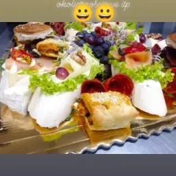 Dekoracyjna taca z przekąskami: mini burgery, sery, wędliny, owoce i warzywa, z tekstem okolicznościowym na górze zachęcającym do zamawiania na święta, sylwestra i inne okazje.