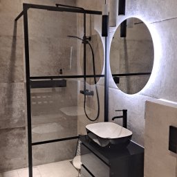 DOBRO-BUD OLEH LANOVENKO - Nowoczesna łazienka z kabiną prysznicową typu walk-in z czarnymi ramami, umywalką nablatową na czarnej szafce z szufladami i okrągłym lustrem z podświetleniem LED oraz wiszącymi lampami...