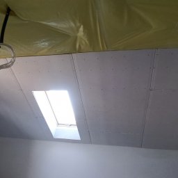 DOBRO-BUD OLEH LANOVENKO - Montaż płyt na poddaszu z oknem dachowym, widoczne przewody elektryczne i drabina.