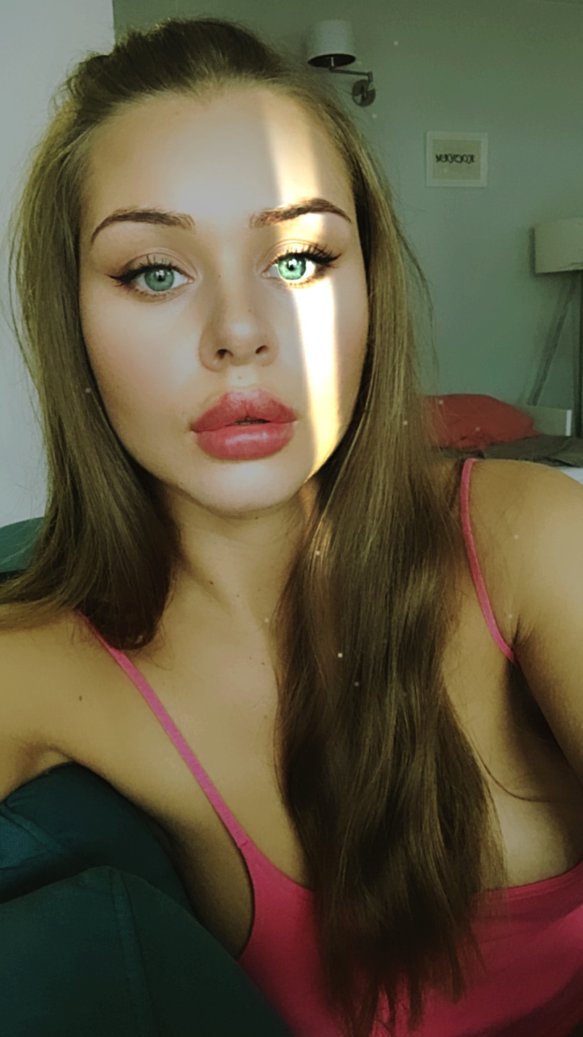 Portret młodej kobiety z długimi, prostymi włosami i intensywnym spojrzeniem, oświetlonej pasmem słonecznego światła na twarzy.