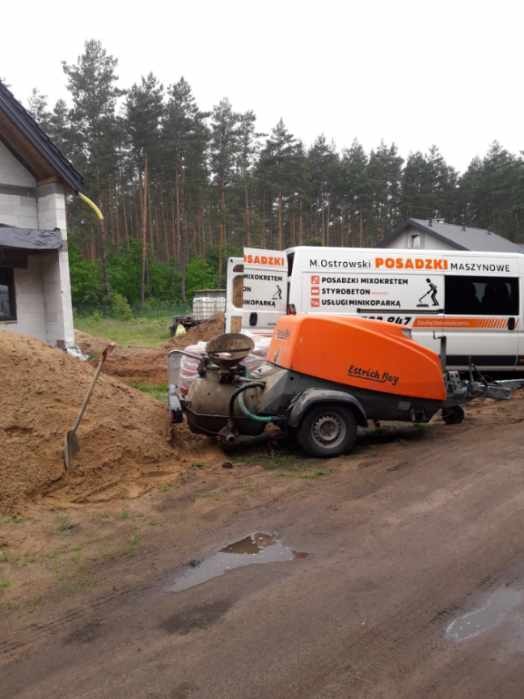 Pompa do wylewania posadzek jastrychowych marki Estrich Boy na placu budowy, obok sterta piasku i bus firmy z reklamą usług w tle.