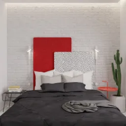 Nowoczesna sypialnia z ceglaną ścianą, asymetrycznymi zagłówkami w kolorze czerwonym i w kropki, czarną pościelą, kaktusem i minimalistycznym oświetleniem.