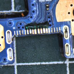 PIK Piotr Dziemiński - Zbliżenie na fragment płyty głównej telefonu z widocznymi elementami elektronicznymi i śladami lutowania, ukazujące precyzję naprawy.