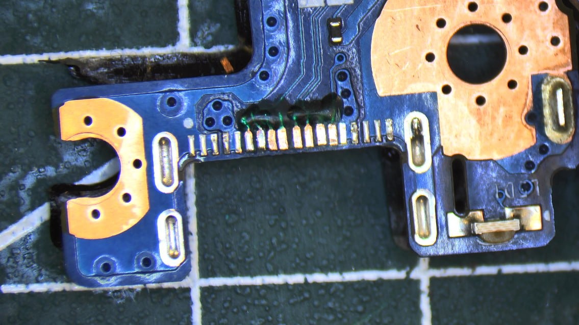 Zbliżenie na fragment płyty głównej telefonu z widocznymi elementami elektronicznymi i śladami lutowania, ukazujące precyzję naprawy.