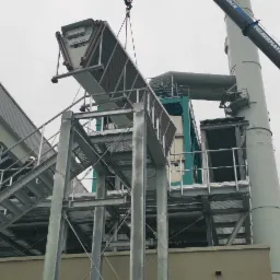 Montaż przemysłowej instalacji wentylacyjnej na zewnątrz budynku, widoczny dźwig Felbermayr podnoszący element konstrukcyjny.